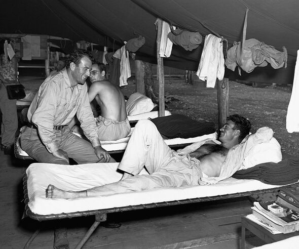 John Wayne chats with a soldier lying on his bunk, New Guinea, 1944. 